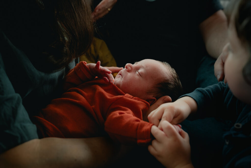 Neugeborenes Baby gehalten von seinen Geschwistern und Eltern