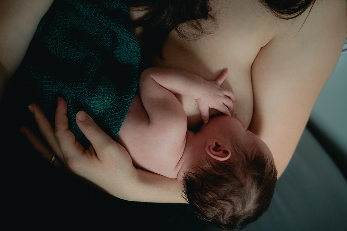 Stillende Mutter im Wochenbett. Babyfotografie zu Hause im Saarland