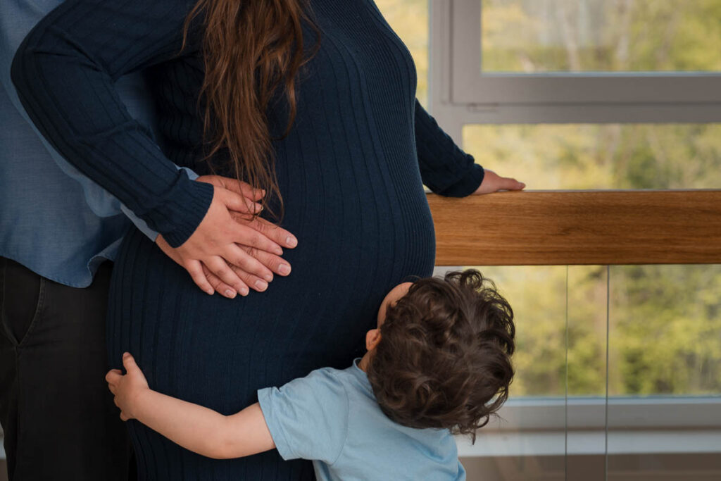 Kind umarmt beim Fotoshooting babybauch